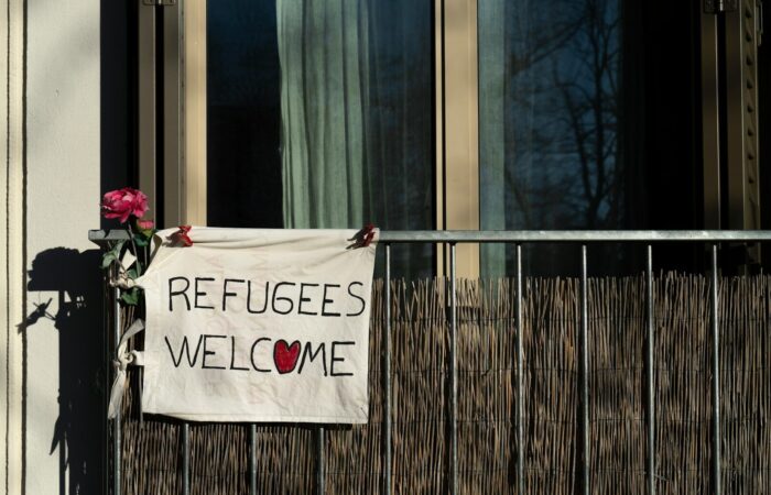 a sign that says refugees welcome on a building