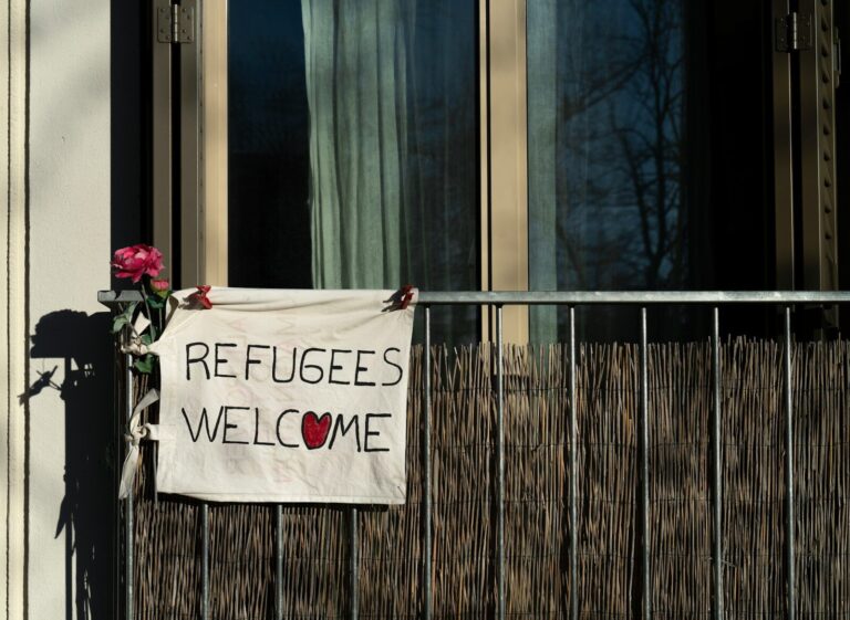 a sign that says refugees welcome on a building